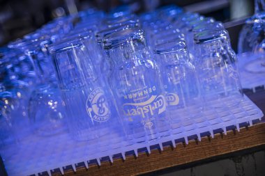 Roma, İtalya 4 Mayıs 2025: boş Carlsberg bira bardakları bir sonraki tur için mavi ışıkla aydınlatılmış plastik bir rafta baş aşağı kuruyor.