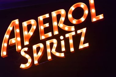 Roma, İtalya 4 Mayıs 2025: Aydınlık aperol spreyi koyu bir arkaplanda sıcak bir şekilde parlıyor, canlı ve davetkar bir atmosfer yaratıyor.