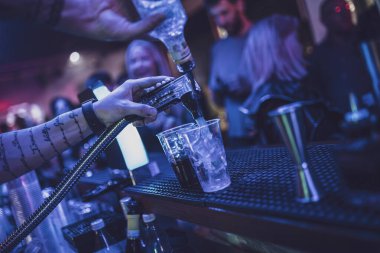 Roma, İtalya, 4 Mayıs 2025: barmen barın tezgahında plastik bardağa kokteyl dolduruyor, buzlu ve arka planda gece hayatının tadını çıkaran insanlar var.