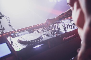 Roma, İtalya 4 Mayıs 2025: DJ bir gece kulübünde müzik karıştırmak için bir öncü kumanda kullanıyor ve kalabalık için heyecan verici bir atmosfer yaratıyor.