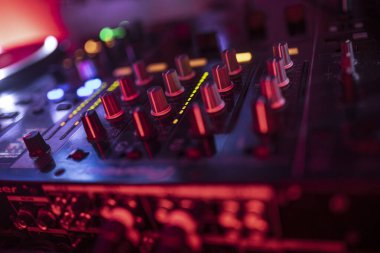 Roma, İtalya, 4 Mayıs 2025: renkli ışıklarla aydınlatılmış bir DJ mikserinin yakın çekimi, bir müzik mekanında canlı bir atmosfer yaratıyor