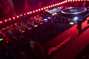 Roma, İtalya 4 Mayıs 2025: Profesyonel DJ karıştırma konsolu kırmızı ışıkta yıkandı, müzik ve eğlence gecesine hazır