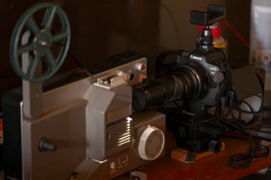 Roma, İtalya 10 Mayıs 2025: Eski ve yeni teknolojiler arasındaki geçiş kavramını yansıtan klasik film projektörünü kaydeden modern dijital sinema kamerası