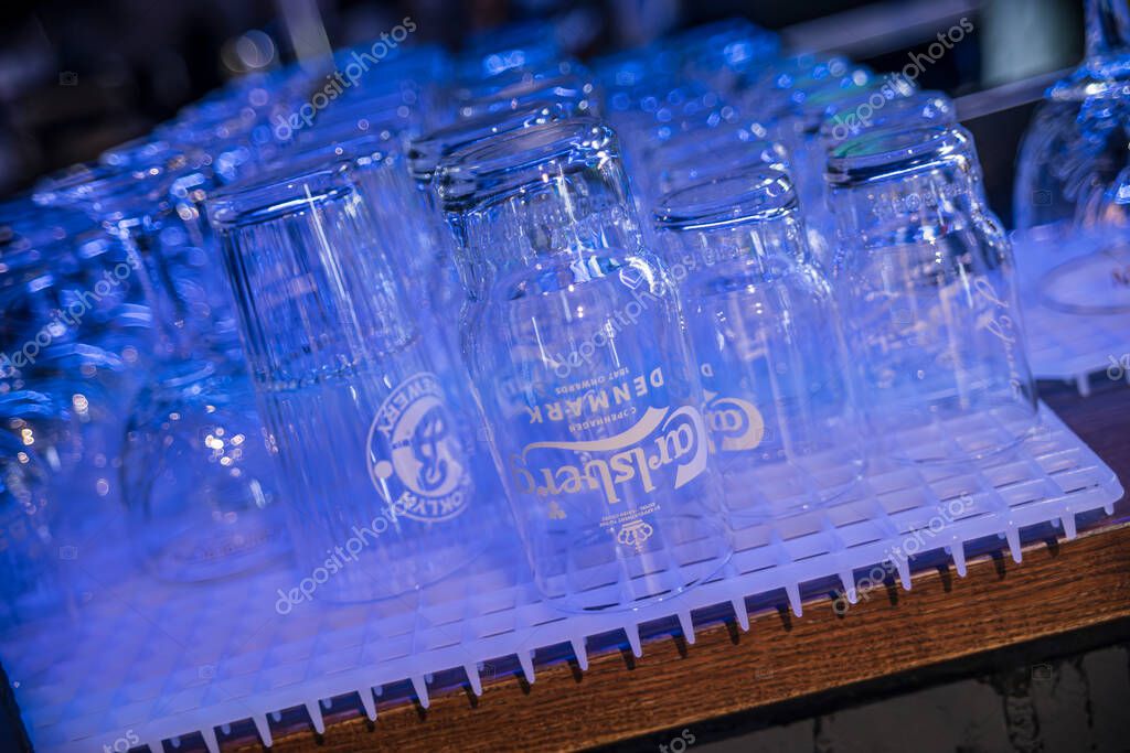 Rome, italy 4 may 2025: empty carlsberg beer glasses are drying upside down on a plastic rack, illuminated by blue light, ready for the next round