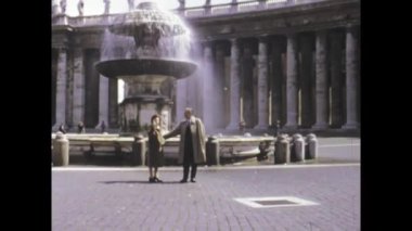 Roma, İtalya Mayıs 1975, 1970 'lerin aydınlık yaz gününde Roma mimari simgesini ele geçiren St. Peter Meydanı, Vatikan' daki ikonik çeşme yakınlarında buluşan turistlerin yer aldığı klasik manzara