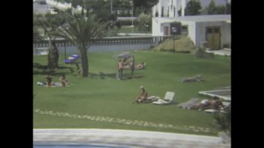 Nijar, İspanya 1975: 1970 'lerdeki kaygısız yaz tatili sırasında turistlerin güneşli Akdeniz otel havuzunda dinlenip yüzdüğü klasik manzara