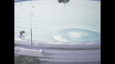 Londra, Birleşik Krallık Mayıs 1973, insanlar güneşli bir günde yüzüp yuvarlak bir havuzda oynuyorlar.