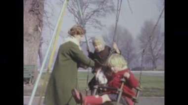 Londra, Birleşik Krallık Mayıs 1963, çocuklar 1960 'larda bir İngiltere oyun alanında anneleriyle birlikte sallanmaktan hoşlanırlar.