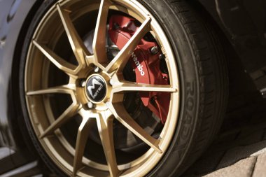 Milan, İtalya, 4 Haziran 2025, kırmızı brembo fren kalibresi ile altın alaşımlı tekerleği kapatın, bir spor arabanın fren sisteminin detaylarını gösteriyor.