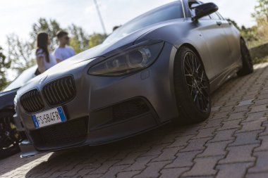 Milan, İtalya. 4 Haziran 2025. Özelleştirilmiş mat gri spor arabanın düşük açılı görüntüsü park edilmiş, modifikasyonlar sergileniyor.