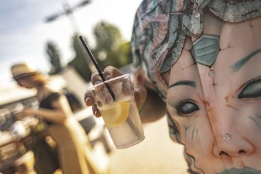 Milan, İtalya 4 Haziran 2025. Eşsiz gömlek giyen bir adam yaz festivalinde limon dilimli ferahlatıcı bir içecek tutuyor. Şenlikli atmosferin tadını çıkarıyor.