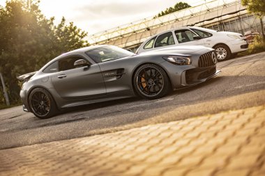 Milan, İtalya 4 Haziran 2025, gri Mercedes Amg Gtr geniş bir otoparkta beyaz bir Citroen 'in yanına park etmiş, lüks ve tasarım performansını ön plana çıkarıyor.