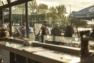 Milan, İtalya. 4 Haziran 2025. Bir hofbrau munchen şemsiyesinin altında bekleyen müşterilerden oluşan bir kafe.