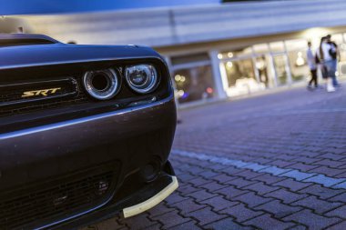 Milan, İtalya, 4 Haziran 2025, parlak Dodge Srt arka planda bulanık insanlar olan bir binanın yakınına park etmiş, akşam ışığında güç ve tarz yayıyor.