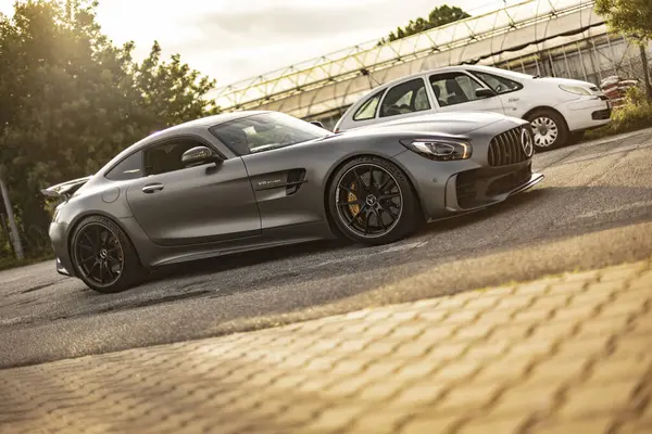 Milan, İtalya 4 Haziran 2025, gri Mercedes Amg Gtr geniş bir otoparkta beyaz bir Citroen 'in yanına park etmiş, lüks ve tasarım performansını ön plana çıkarıyor.