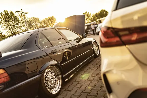 Milan, İtalya. 4 Haziran 2025. Otomotiv tutkusu ve akort kültürünü gözler önüne seren, bir araba yarışmasında altın gün batımını yansıtan parlak krom jantlı BMW e36.