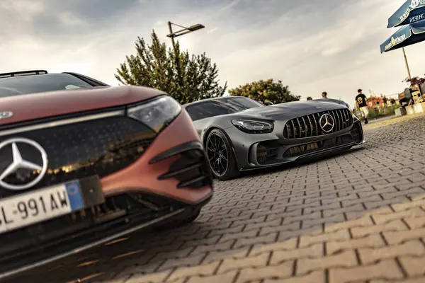 Milan, İtalya 4 Haziran 2025, iki Mercedes Benz 'in alçak açılı görüntüsü kaldırım taşlı bir caddeye park edilmiş, lüks ve otomotiv tasarımı sergileniyor.