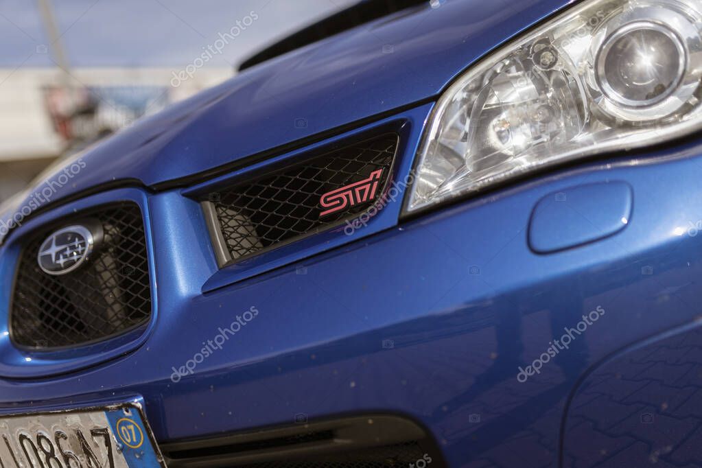 Milan, italy 4 june 2025, close up of a blue subaru impreza wrx sti, highlighting the iconic grille with the pink sti logo and the clean headlight