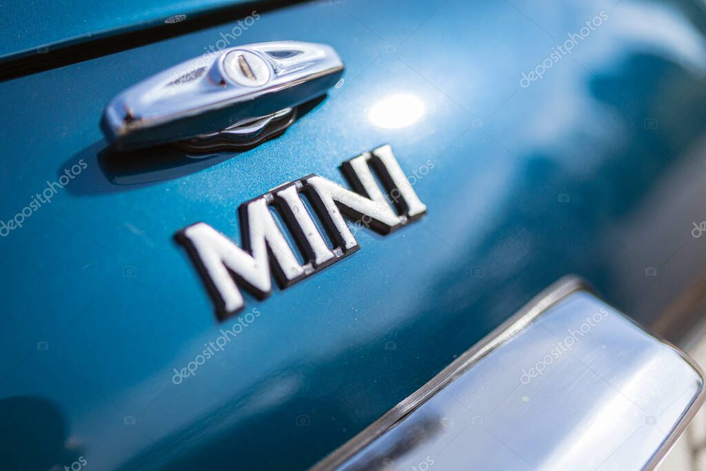 Milan, italy 4 june 2025, close up of the iconic mini cooper logo on a turquoise vintage car, highlighting its timeless design and automotive heritage