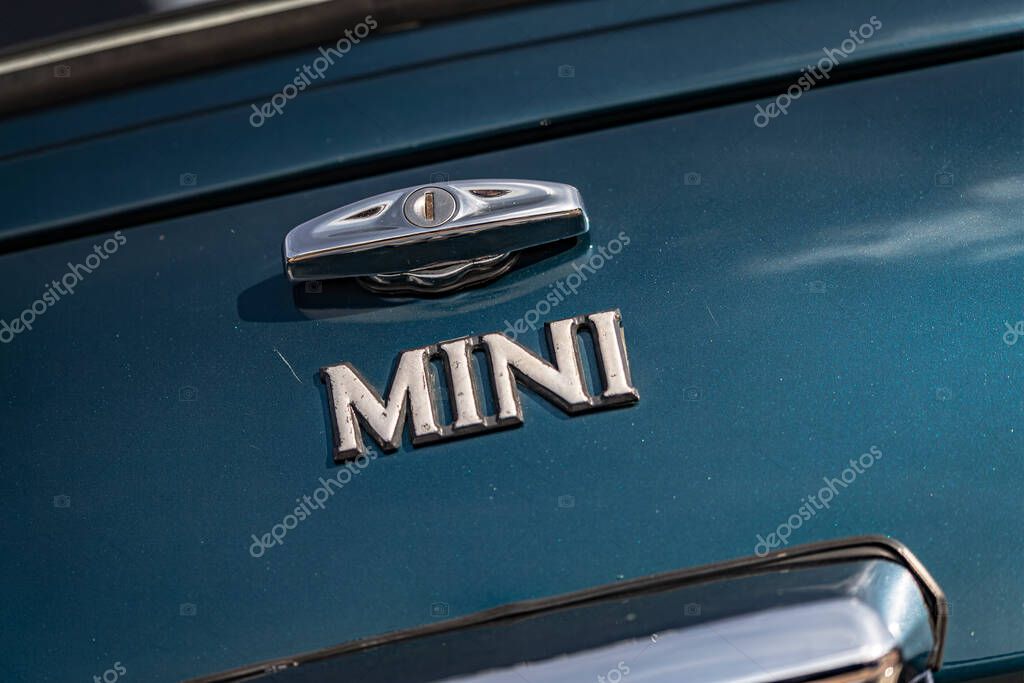 Milan, italy 4 june 2025, close up of a classic mini cooper's trunk, highlighting the chrome handle, keyhole, and iconic mini logo against a teal colored backdrop
