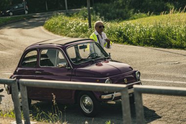 Milan, İtalya, 4 Haziran 2025, güneşli bir yaz gününde 500 'lü yılların klasik mitinginde yansıtıcı yelek giyen mareşal trafiği yönetiyor.