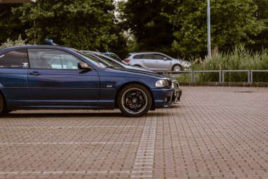 Milan, İtalya 4 Haziran 2025, koyu mavi bir BMW arabası asfaltlı bir otoparka park edilmiş, diğer arabalar da arka planda görünüyor.