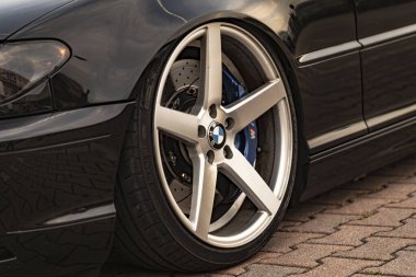 Milan, İtalya 4 Haziran 2025, siyah bir BMW aracında mavi fren kalibreli gümüş alaşımlı tekerlek, tuğladan bir kaldırıma park edilmiş.