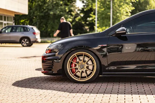 Milan, İtalya 4 Haziran 2025, modern akortlu Volkswagen golf gti şehrin parke taşı sokağına park edilmiş altın jantlar.