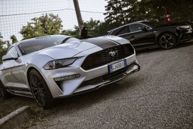 Roma, İtalya, 17 Haziran 2025, parlak gümüş Ford Mustang yarış pistinin yakınına park edilmiş, güç ve hız gösteriyor.