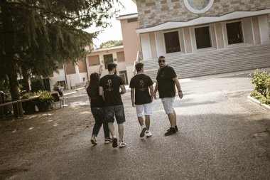 Roma, İtalya, 17 Haziran 2025, aynı tişörtleri giyen dört personel iş yerlerinden uzaklaşıyor, birlik ve dostluk duygusunu iletiyorlar.