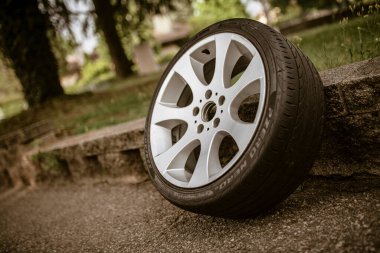Roma, İtalya, 17 Haziran 2025, bir park ortamında alçak bir taş duvara yaslanmış bir araba tekerleğinin kapanışı araç bakımı, yol kenarı acil durumları veya lastik değişiklikleri temaları öneriyor.