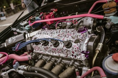 Roma, İtalya, 17 Haziran 2025, özelleştirilmiş bir otomobil motorunun kapağı pembe ve mor yedek parça, benzersiz ve kişiselleştirilmiş bir tasarım sergiliyor.
