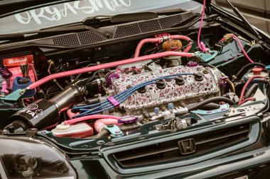 Roma, İtalya, 17 Haziran 2025. Pembe hortumlar, dekoratif kapak ve diğer kişiselleştirilmiş modifikasyonlar içeren özelleştirilmiş bir araba motorunun kapağı.