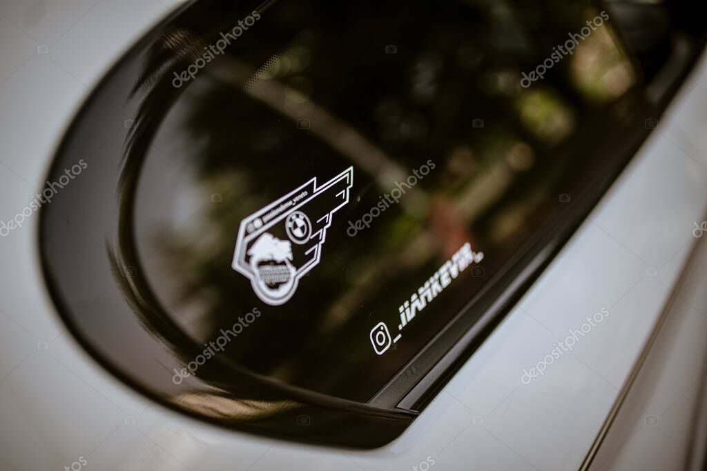 Rome, italy 17 june 2025, close up of a bmw logo sticker reflecting in a car's tinted window, showcasing car enthusiasm and brand loyalty