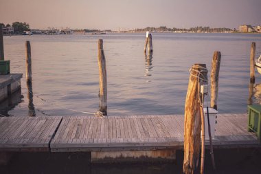 Gün batımında sakin bir iskele manzarası. Chioggia, İtalya 'da sakin sular ve uzak teknelerle dolu.