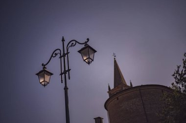 Zarif sokak lambası, Roma, İtalya 'daki tarihi çan kulesine alacakaranlık usulca çökerken sahneyi aydınlatıyor. Huzurlu ve canlandırıcı bir atmosfer yaratıyor.