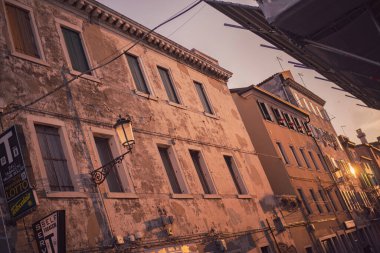 Chioggia, İtalya 21 Haziran 2025, eski, yıpranmış binalar günbatımının sıcacık parıltısıyla Chioggia ve sottomarina, İtalya 'da göze çarpan bir sokak lambası ile yıkandı.