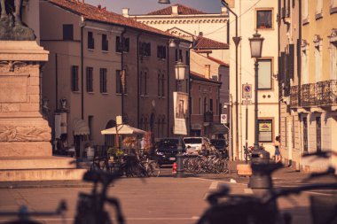 Rovigo, İtalya 21 Haziran 2025, güneşli bir günde İtalya, Rovigo 'da park etmiş bisikletler ve arabalar.