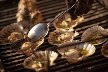 Kaşıkla bir şefin yanına yaklaş, ızgara ızgarada sarımsak ve maydanozla tatlandırılmış taze midye pişir, ağız sulandıran deniz ürünleri tabağı yap.