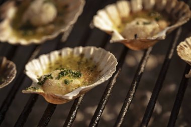 Taze deniz tarakları, sarımsak, maydanoz ve tereyağı ile tatlandırılmış ızgarada ızgara yaparak ağız sulandıran deniz ürünleri tabağı oluşturuyorlar.