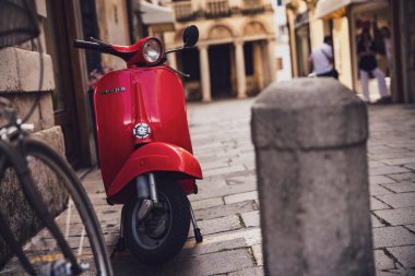 Padova, İtalya, 30 Haziran 2025, canlı kırmızı Vespa scooter Padua, İtalya 'da büyüleyici bir kaldırım taşı caddesinde park edilmiş, zamansız stil ve İtalyan cazibesini yakalıyor.