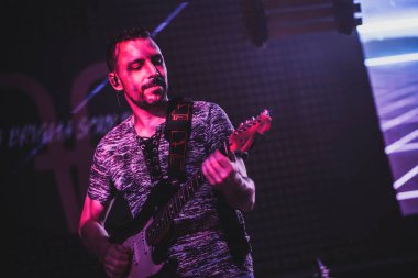 Padua, İtalya 8 Temmuz 2025, canlı konser sırasında mor sahne ışıklarıyla aydınlatılmış elektro gitar çalarken konsantre olan müzisyen.