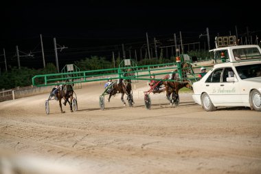 Padua, İtalya, 8 Temmuz 2025, gece hipodromda koşan atlar, ardından da bir araba.