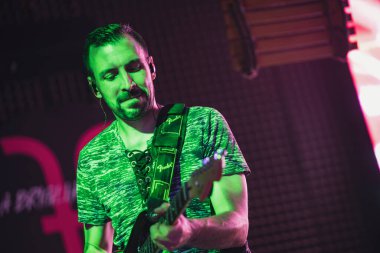 Padua, İtalya 8 Temmuz 2025, müzisyen sahnede ustaca elektro gitar çalıyor, canlı yeşil ve pembe ışıklarla aydınlatılıyor, dinamik bir konser ortamı yaratıyor.