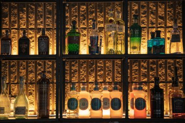 Padua, İtalya 8 Temmuz 2025, iyi aydınlatılmış bir bar rafında renkli içki şişeleri sergileniyor, dokulu bir duvara karşı çeşitli ruhları vurguluyor, canlı bir ortam yaratıyor.