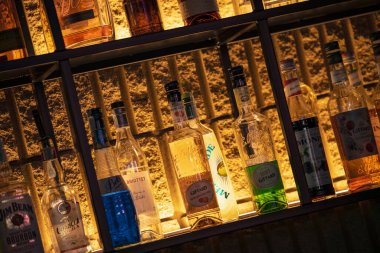 Padua, İtalya 8 Temmuz 2025, çeşitli içki şişeleri sıcak bir bar rafında sergileniyor, farklı renkleri ve etiketleri vurguluyor, davetkar bir atmosfer yaratıyor.