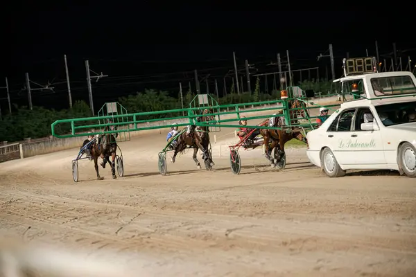 Padua, İtalya, 8 Temmuz 2025, gece hipodromda koşan atlar, ardından da bir araba.