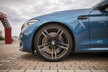 Roma, İtalya 18 Temmuz 2025, tuğla kaldırıma parkedilmiş parlak mavi spor araba, ayrıntılı alaşım tekerleği, fren sistemi ve parlak tasarımı sergileniyor.