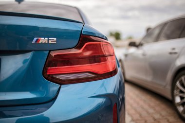 Roma, İtalya 18 Temmuz 2025. Metalik mavi BMW M2 'nin arka lambası tuğladan yapılmış bir otoparka park edilmiş.