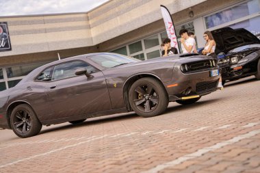 Roma, İtalya 18 Temmuz 2025, bir grup tamirci garajlarının önünde park etmiş bir Dodge meydan okuyan kaslı arabaya hayran.